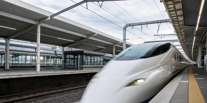 A shinkansen pulling into a Japanese station platform, seen from the platform edge